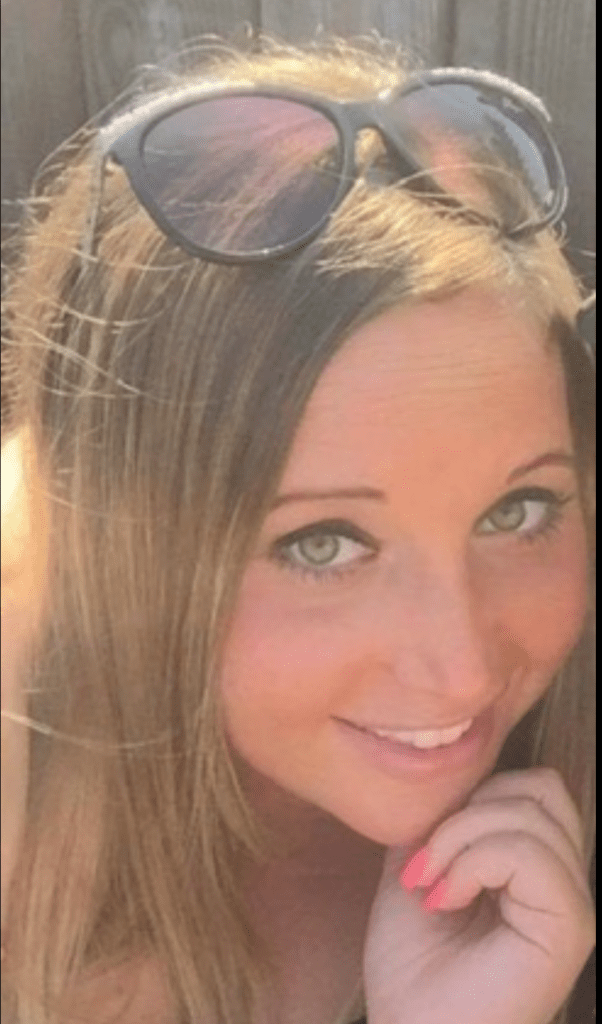 Close-up of a smiling woman with light brown hair and green eyes.