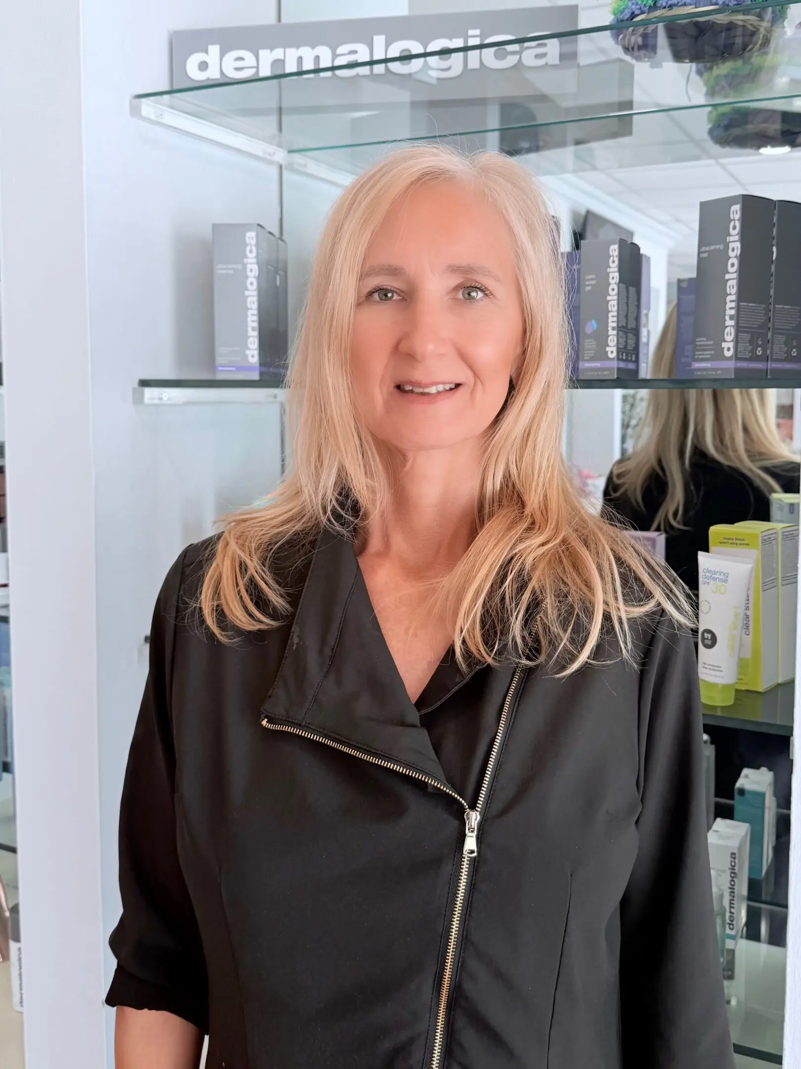 Smiling woman with long blonde hair wearing a black jacket.